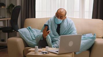 Sick man with high body temperature during covid-19 wearing a mask during a video call with his doctor.