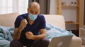 Ill man at home talking online with his doctor, holding a bottle with pills video