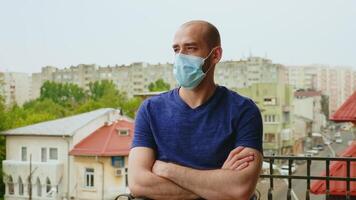 verdrietig Mens met beschikbaar masker Aan de balkon omdat van coronavirus isolatie. video