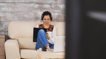 Woman writing notes on clipboard during a work video call while working from home.