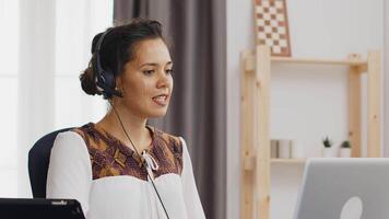 gelukkig bedrijf vrouw vervelend koptelefoon gedurende een video telefoontje terwijl werken van huis kantoor.