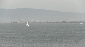 san francisco, ca, 2016 - barco a vela e lancha em baía nublado cinzento neblina colinas dentro fundo video