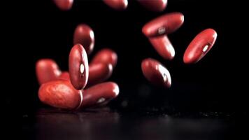 Falling red beans on a black background. Filmed on a high-speed camera at 1000 fps. High quality FullHD footage video