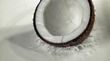 Half of the coconut falls into the milk with splashes. Filmed on a high-speed camera at 1000 fps. High quality FullHD footage video