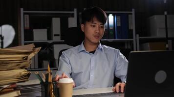 utmattad asiatisk ung affärsman arbetstagare arbetssätt på tabell i kontor. video