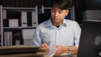 Exhausted Asian young businessman worker working on table in office. video