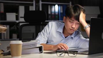 Exhausted Asian young businessman worker working on table in office. video