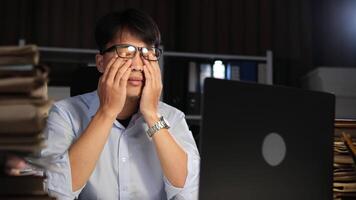 Exhausted Asian young businessman worker working on table in office. video