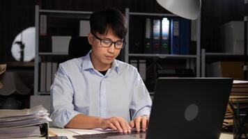 esausto asiatico giovane uomo d'affari lavoratore Lavorando su tavolo nel ufficio. video