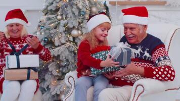 Granddaughter exhcanging Christmas gift present boxes with amazed happy senior grandfather at home video