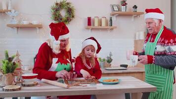 Senior man with cups hot chocolate walking into Christmas home kitchen to grandmother and grandchild video