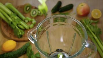 Vegetables fall in blender, super slow motion. Green smoothie in blender, top view. Healthy and vegetarian food concept video