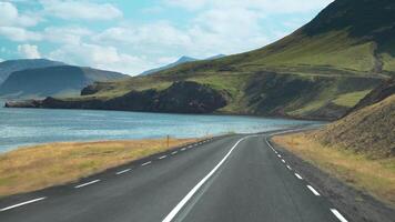 coche conducción en el la carretera a Islandia. ver de el camino, montañas y el bahía desde el dentro de el coche. la carretera número 1 es de islandia principal la carretera. hermosa naturaleza de Islandia. 4k video