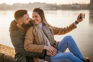 contento Pareja tomando selfie mientras disfrutar gasto hora juntos exterior. foto