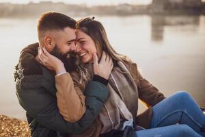 contento Pareja abrazando mientras disfrutar sentado por el río. foto