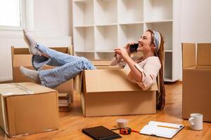 Happy woman using phone and having fun while moving into new apartment. photo