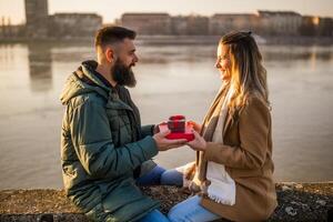 Man giving presents to his woman while they enjoy spending time together outdoor. photo