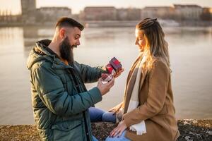 Woman giving presents to her man while they enjoy spending time together outdoor. photo