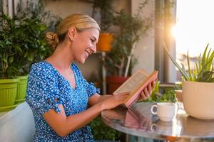 Beautiful woman enjoys reading book and drinking coffee on her balcony. photo