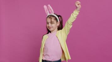 Confident cheery girl showing dance moves in the studio, feeling cheerful and positive about easter holiday festivity. Talented child dancing around and wearing bunny ears. Camera A. video