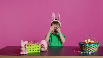 glimlachen schattig kind spelen kijkje een boe spel met geschilderd kleurrijk eieren, hebben pret met Pasen decoraties en regelingen Aan camera. enthousiast blij jongen wezen opgewonden over vakantie. camera b. video