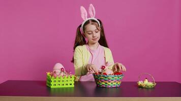 Sleepy little girl yawning while she arranges easter eggs for festive decorations, almost falling asleep at the table where she decorates for spring holiday celebration. Tired schoolgirl. Camera B video