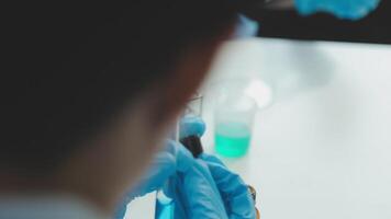 médico mano tomando un sangre muestra tubo desde un estante con máquinas de análisis en el laboratorio fondo, técnico participación sangre tubo prueba en el investigación laboratorio. video