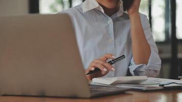 Asian Businesswoman Using laptop computer and working at office with calculator document on desk, doing planning analyzing the financial report, business plan investment, finance analysis concept. video