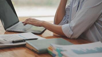 Asian Businesswoman Using laptop computer and working at office with calculator document on desk, doing planning analyzing the financial report, business plan investment, finance analysis concept. video