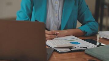Asian Businesswoman Using laptop computer and working at office with calculator document on desk, doing planning analyzing the financial report, business plan investment, finance analysis concept. video