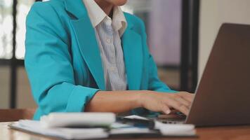Asian Businesswoman Using laptop computer and working at office with calculator document on desk, doing planning analyzing the financial report, business plan investment, finance analysis concept. video