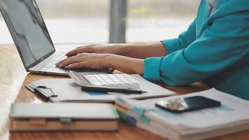 Asian Businesswoman Using laptop computer and working at office with calculator document on desk, doing planning analyzing the financial report, business plan investment, finance analysis concept. video