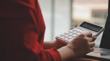 femme d'affaires asiatique utilisant un ordinateur portable et travaillant au bureau avec un document de calculatrice sur le bureau, faisant la planification en analysant le rapport financier, l'investissement dans le plan d'affaires, le concept d'analyse financière. video