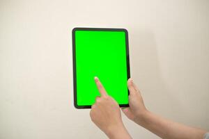 hand is holding a tab with green screen on a white isolated background photo