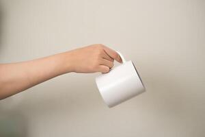 hand is holding a mug or glass on a white isolated background photo