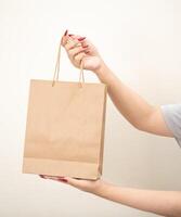 hand holding a shopping paper bag against a white isolated background photo