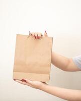 hand holding a shopping paper bag against a white isolated background photo