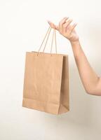 hand holding a shopping paper bag against a white isolated background photo