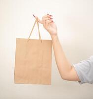 hand holding a shopping paper bag against a white isolated background photo