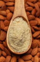 Fresh almond flour in a  wooden spoon and almonds photo
