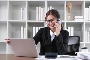 Young Asian woman using laptop to do financial transaction and plan finances and investments through online banking photo