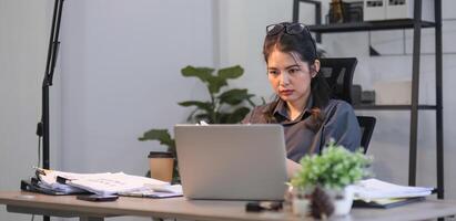 Puzzled confused asian woman thinking hard concerned about online problem solution looking at laptop screen, worried serious asian businesswoman focused on solving difficult work computer task photo