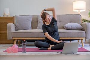 joven asiático deportivo aptitud mujer entrenador hacer práctica vídeo en línea formación yoga ordenador portátil en vivo habitación a hogar foto