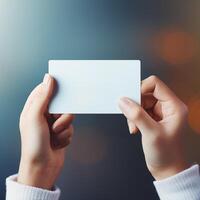 AI generated Woman hand holding blank white business card mockup on blurred background photo