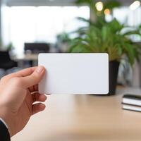 AI generated Close up of Hand showing blank white business card mockup on blurred office background photo