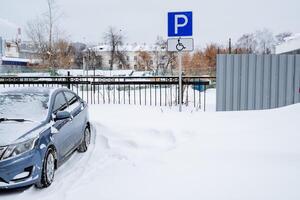 cubierto de nieve estacionamiento espacio. estacionamiento para el desactivado. la carretera estacionamiento firmar para el desactivado. especial estacionamiento sitio foto