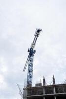 A crane builds a high-rise building, a construction site, a concrete building. Blue faucet. photo