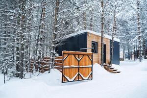 Country house made of wood in the forest. Visiting the cottage in winter. Wooden railings, walls and fence. Forest landscape in the snow photo