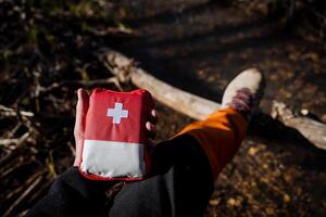 The first aid kit is red. A bag of medicines for first aid in a camping trip in nature. Camping equipment, medicines in travel. photo