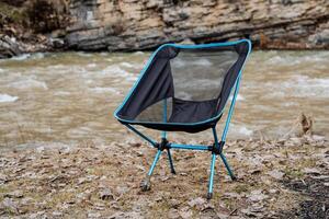 Folding chair easy to relax, camping equipment, compact folding chair on legs, relaxation in nature outside the city. photo